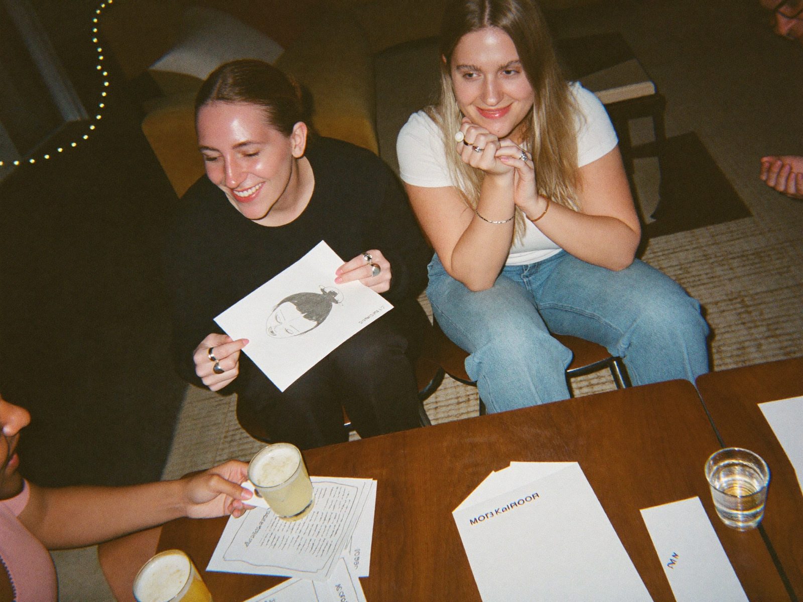 A host's living room mid-evening, four people laughing around a coffee table